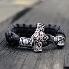 Cargar imagen en el visor de la galería, Thor's Hammer Mjolnir leather bracelet with intricate Norse design on a rustic surface, symbolizing Viking strength and style.