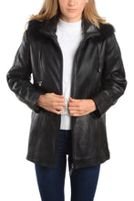Load image into Gallery viewer, Women's black lamb leather jacket with detachable fox fur hood and braided trim, worn over a white top, stylish winter fashion.