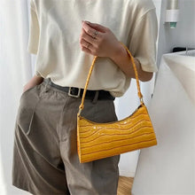 Cargar imagen en el visor de la galería, Person holding a yellow leather shoulder bag, wearing a white shirt and brown trousers, showcasing a stylish fashion accessory.