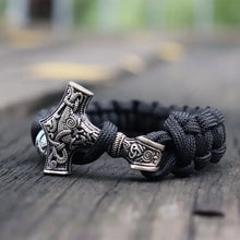 Cargar imagen en el visor de la galería, Thor's Hammer Mjolnir leather bracelet with detailed Viking design on a wooden surface