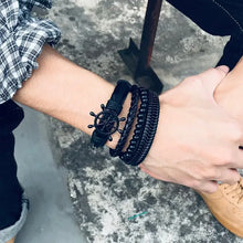 Cargar imagen en el visor de la galería, Man's wrist wearing Vnox 4-piece vegan leather braided wrap bracelets with zinc alloy accents outdoors.