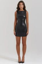 Load image into Gallery viewer, Model wearing a vegan leather mini black dress, showcasing sleek and chic design for stylish night outs or special occasions.