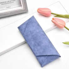 Cargar imagen en el visor de la galería, Blue PU leather sunglasses case on a table, surrounded by pink tulips. Stylish and compact glasses storage solution.