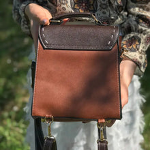 Load image into Gallery viewer, Person holding a Bumblebee vegan leather backpack with sleek design and brown color, ideal for professionals.