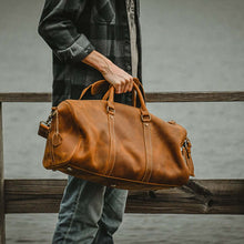 Cargar imagen en el visor de la galería, The Dagny Weekender | Large Leather Duffle Bag held by person outdoors, showcasing style and functionality for travelers.