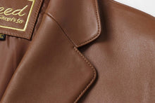 Cargar imagen en el visor de la galería, Close-up of REED Men's Premium Lambskin Leather Blazer showcasing the fine stitching and luxurious brown leather texture.