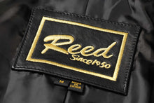 Cargar imagen en el visor de la galería, REED brand label on black fabric with gold embroidery, featuring text 'Reed Since 1950' and 'Made in China' tag.