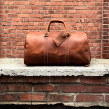 Cargar imagen en el visor de la galería, The Dagny Weekender | Large Leather Duffle Bag in full-grain leather on brick background, ideal for stylish and organized travel adventures.