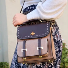 Load image into Gallery viewer, Woman holding a Bumblebee vegan leather backpack with sleek design and multiple compartments, ideal for professionals seeking style and functionality.