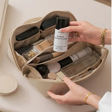 Cargar imagen en el visor de la galería, Person organizing makeup products in a beige high-capacity leather cosmetic organizer with multiple compartments.