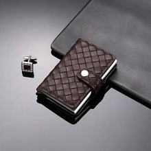 Load image into Gallery viewer, Elegant leather RFID cardholder with secure clasp and textured design, shown next to a stylish cufflink on a sleek surface.
