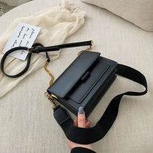 Cargar imagen en el visor de la galería, Luxury designer leather crossbody shopping bag with gold accents on a cream sofa, held by a hand, showcasing chic fashion style.