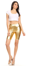 Cargar imagen en el visor de la galería, Model wearing shiny metallic gold bike shorts with white crop top, stretchy unisex design, made in USA.