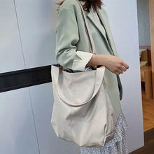 Load image into Gallery viewer, Woman carrying a soft vegan leather shoulder bag with large capacity, showcasing luxury and elegance in a light indoor setting.