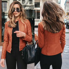 Load image into Gallery viewer, Woman wearing a faux leather jacket in brown, styled with black pants and sunglasses, showcasing its sleek design in a city setting.