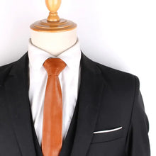 Cargar imagen en el visor de la galería, Brown polyurethane leather tie for men paired with a black suit on a mannequin, showcasing vegan fashion elegance.