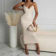 Cargar imagen en el visor de la galería, Woman in plus size beige leather spaghetti strap dress, holding a purse, standing in a modern minimalist room.