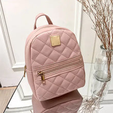 Cargar imagen en el visor de la galería, Pink quilted mini backpack for women made from PU leather, featuring a zipper pocket and gold-tone accents, styled on a mirrored surface.