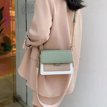Cargar imagen en el visor de la galería, Woman wearing a stylish green and white leather crossbody bag for shopping, paired with a beige coat.