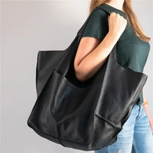 Load image into Gallery viewer, Woman holding a soft luxury vegan leather shoulder bag, showcasing its large capacity and elegant design.