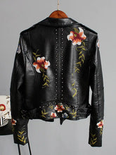 Load image into Gallery viewer, Floral Print Faux Leather Jacket with bold floral design and edgy punk rock elements, showcasing unique style on a hanging display.