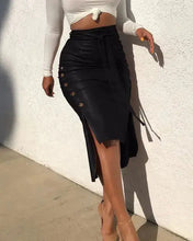 Load image into Gallery viewer, Woman wearing a high-waist faux leather skirt with belt and button trim paired with a white long-sleeve crop top.