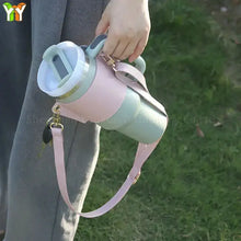 Load image into Gallery viewer, Person carrying a cup in a pink PU leather coffee cup carrier with a shoulder strap outdoors.
