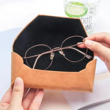 Cargar imagen en el visor de la galería, Person placing eyeglasses into a stylish PU leather sunglasses case, highlighting practical eyewear protection.