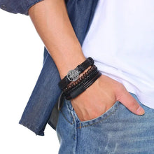 Cargar imagen en el visor de la galería, Men's hand wearing Vnox 4Pc Braided Wrap Leather Bracelets, featuring vegan leather and zinc alloy, with a rugged lace-up clasp design.