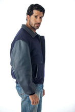 Charger l'image dans la galerie, REED men's leather varsity bomber jacket, made in USA, featuring top-grain leather sleeves and trim, modeled by a man in jeans.