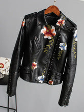 Load image into Gallery viewer, Floral print faux leather jacket with edgy punk style and romantic floral designs, hung on a wooden hanger.