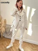 Load image into Gallery viewer, Woman wearing a white faux leather fur coat, styled with casual white pants and boots, standing in a well-lit room.