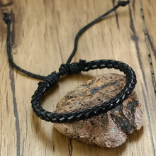 Cargar imagen en el visor de la galería, Black braided vegan leather bracelet on wooden surface, featuring adjustable lace-up clasp for a rugged, stylish look.