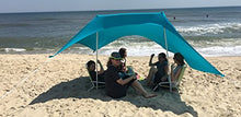 Charger l'image dans la galerie, eZthings UV Light Sun Shade Protection Beach Shelter with sandbag anchors set up on sandy beach, offering shade to a group of people.