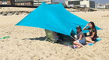 Charger l'image dans la galerie, Family enjoying shade under eZthings UV Light Sun Shade Protection Beach Shelter with sandbag anchors on a sunny beach.