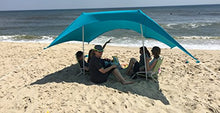 Charger l'image dans la galerie, Group relaxing under eZthings UV light sun shade beach shelter with sandbag anchors, providing sun protection on the sandy beach.