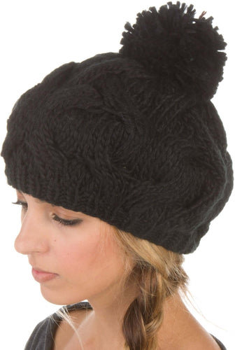 Black cable knit pom pom slouch hat on person, featuring thick knit and cozy stretch, perfect for winter fashion. Made from 100% acrylic.