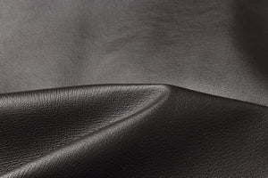 Close-up of genuine leather fabric texture in dark brown color, perfect for luxury garments like bomber jackets.