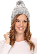 Cargar imagen en el visor de la galería, Woman wearing a Greer unisex heathered knit pom pom beanie hat with a stylish design and smiling face.
