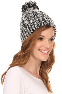 Smiling woman wearing a Greer unisex heathered textured knit pom pom beanie hat in black and white.