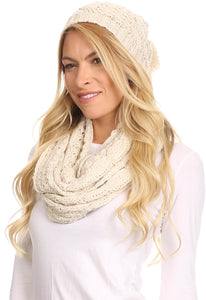 Woman wearing Haile metallic threaded woven classic knit beanie and infinity scarf set in cream color with pom pom detail.