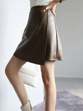 Load image into Gallery viewer, Woman wearing a high-waist dark brown PU leather A-line split short skirt, showcasing chic design and flattering silhouette.
