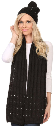 Woman wearing a Kae jewel-studded cable knit beanie and scarf set in black with pom-pom, showing stylish winter outfit.