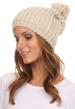 Charger l&#39;image dans la galerie, Unisex cable knit beanie hat with large pom pom, shown on model. Features slouchy fit, one-size, beige color, ideal for winter fashion.
