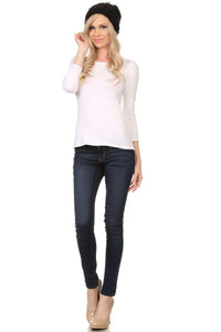Model wearing a black cable knit beanie with pom pom, white top, dark skinny jeans, and heels, showcasing the casual hat style.
