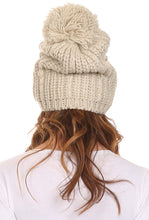 Charger l&#39;image dans la galerie, Ivory cable knit beanie hat with large pom pom, worn by woman. Stylish unisex winter accessory. One size fits most, slouchy fit.
