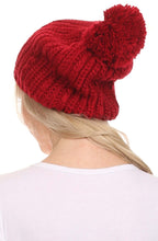 Charger l&#39;image dans la galerie, Red cable knit beanie with large pom pom, worn by model, showcasing slouchy fit and wide design for versatile wear.
