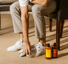 Cargar imagen en el visor de la galería, Man using Leather Cleaner on shoes with Leather Honey bottles on the floor.
