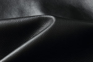 Close-up of luxurious black genuine leather texture, highlighting softness for jackets.