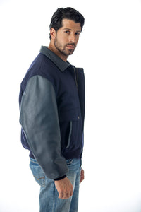 REED men's leather varsity bomber jacket, made in USA, featuring top-grain leather sleeves and trim, modeled by a man in jeans.